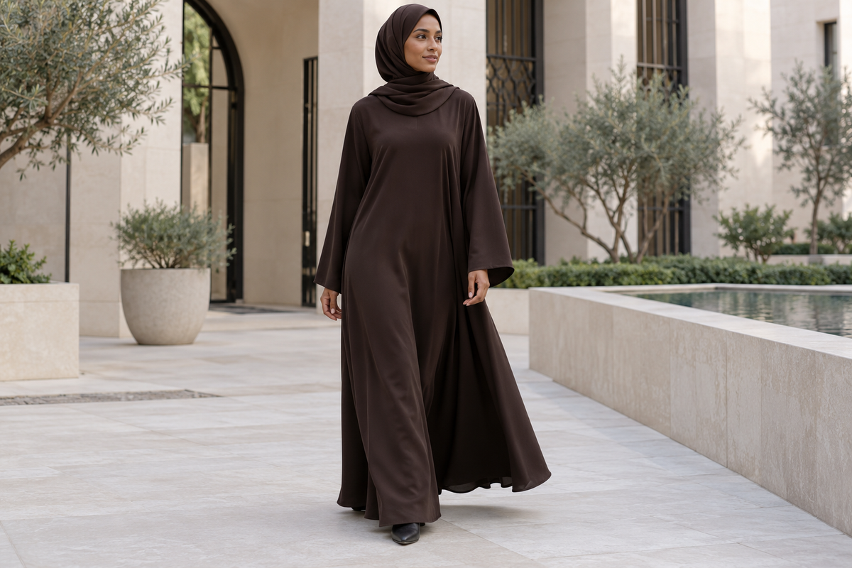 Model in an espresso abaya and matching hijab in a pale stone courtyard