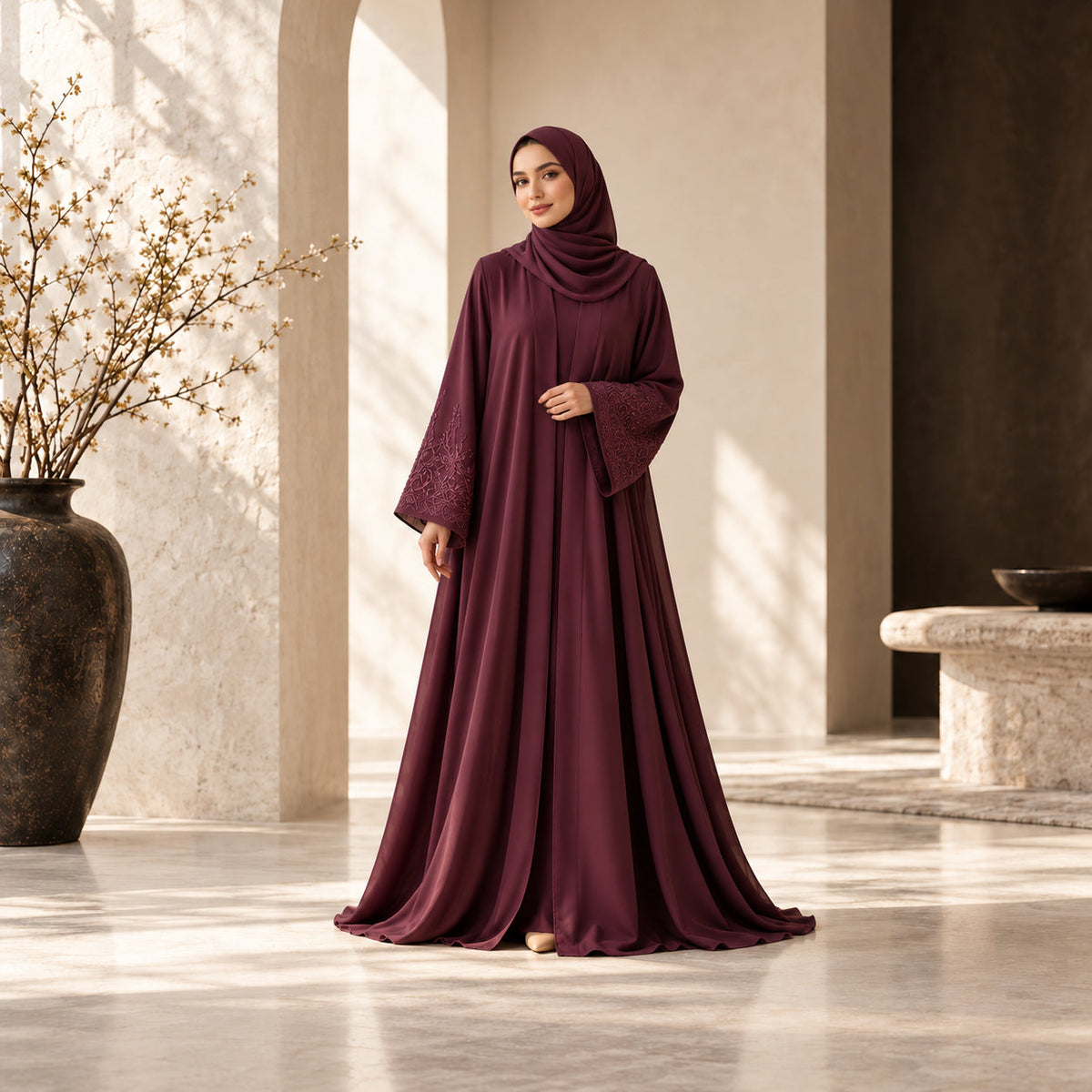 Woman wearing a plum embroidered abaya and matching hijab in a sunlit ivory courtyard